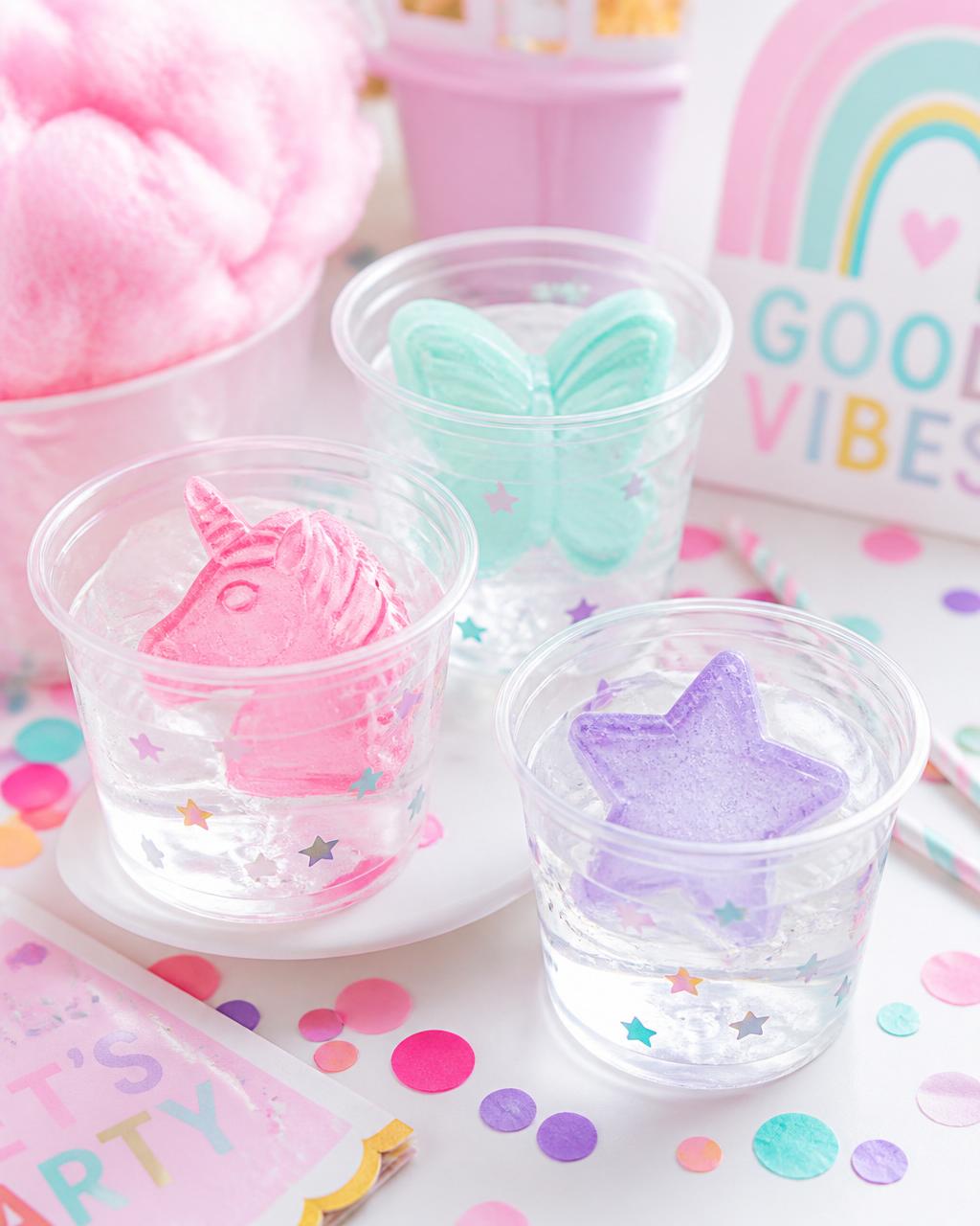 Glacée Fête colorful pastel party ice — pink unicorn, mint butterfly, and lavender star shapes in clear cups surrounded by confetti